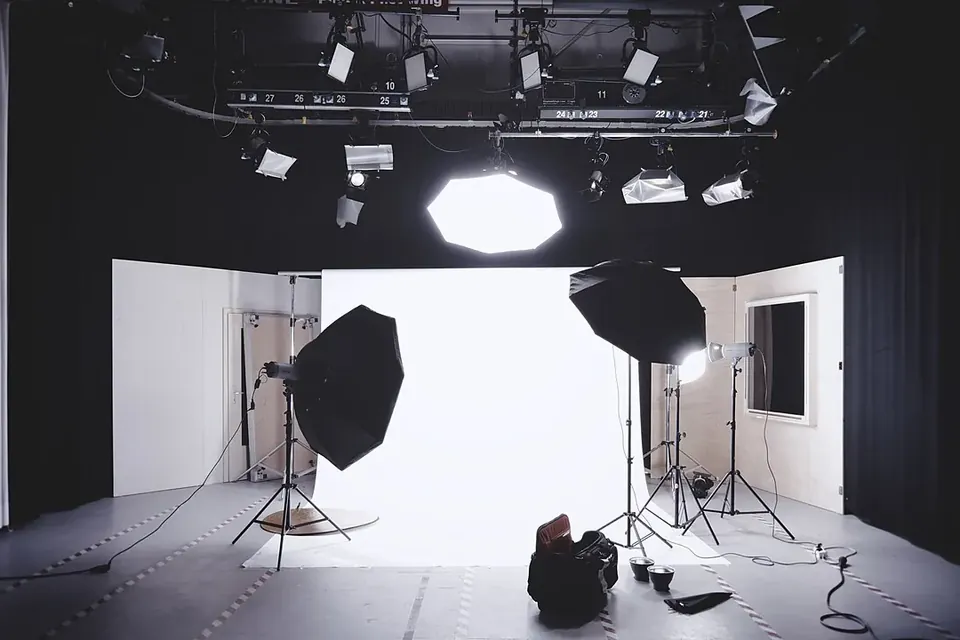 A photo studio with a white backdrop, softbox lights on stands and lighting rigs hanging from the ceiling